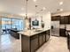 Modern kitchen with stainless steel appliances and an island overlooking living room at 7472 Oakmoss Loop, Davenport, FL 33837