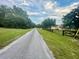 Long gravel driveway leading to a home with a black fence at 13659 Sw 115Th Pl, Dunnellon, FL 34432