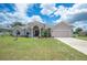 Tan one-story house with a three-car garage and manicured lawn at 4046 Dinner Lake Way, Lake Wales, FL 33859