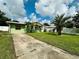 Ranch-style home with a green exterior, driveway, and palm tree at 6004 Hilltop E Ln, Lakeland, FL 33809