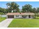 Brick ranch home with a brown door, attached garage, and a well-manicured lawn at 4314 Ridge Rd, Lakeland, FL 33811