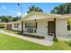 White brick home with brown accents, a covered porch, and a manicured lawn at 4314 Ridge Rd, Lakeland, FL 33811