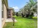 Landscaped backyard with a grassy area and tropical plants at 2316 Midnight Pass Ct, The Villages, FL 32162