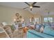 Cozy living room featuring teal sofa, wicker chairs, wood-look floors, and a view into the dining area at 7031 Red Grange Boulevard Ave, Indian Lake Estates, FL 33855
