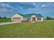 Single-story home with a green metal roof and well-manicured lawn at 7031 Red Grange Boulevard Ave, Indian Lake Estates, FL 33855