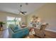 Comfortable living room with teal sofa and wicker chairs, offering natural light and wood-look flooring at 7031 Red Grange Boulevard Ave, Indian Lake Estates, FL 33855