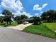 Concrete driveway leading to a two-car garage with lush landscaping and mature trees at 1211 Cr 436, Lake Panasoffkee, FL 33538