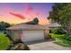 Brick ranch home with attached garage, American flag, and landscaping at sunset at 696 Caribbean Dr, Lakeland, FL 33803