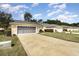 Exterior view of a single-story house with a three-car garage and a neatly maintained lawn at 15695 Sw 13Th Cir, Ocala, FL 34473