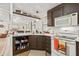 Kitchen with dark brown cabinets, white appliances, and open shelving at 6505 Raintree Ne Ln, Winter Haven, FL 33881