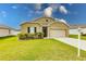 Tan one-story house with a two-car garage and landscaped yard at 6048 Forest Ridge Ln, Winter Haven, FL 33881