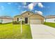 Tan one-story house with a two-car garage and landscaped yard at 6048 Forest Ridge Ln, Winter Haven, FL 33881