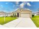 Tan one-story house with a two-car garage and landscaped yard at 6048 Forest Ridge Ln, Winter Haven, FL 33881
