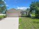 Tan one-story house with a two-car garage and manicured lawn at 5411 Great Egret Dr, Leesburg, FL 34748