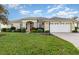 One-story house with a red door and two-car garage at 24429 Madewood Ave, Leesburg, FL 34748