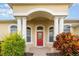 Inviting home exterior with a red front door and lush landscaping at 24429 Madewood Ave, Leesburg, FL 34748