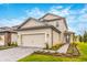 Two-story house with beige siding, gray-stone driveway, and landscaped front yard at 7737 Somersworth Dr, Kissimmee, FL 34747