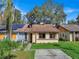 Tan house with brown roof, solar panels, and a small front yard at 1057 Old South Dr, Lakeland, FL 33811