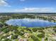 Wide aerial view of a lake reflecting the sky and surrounding houses at 2002 Amesbury Dr, Auburndale, FL 33823