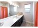 Bathroom with double vanity, large mirror, and coral-colored shower curtain at 2436 Chateau Loop, Kissimmee, FL 34741