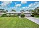 Single story home with attached garage, manicured lawn, and mature landscaping at 7491 Limonia Dr, Indian Lake Estates, FL 33855