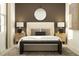 Sophisticated bedroom with a beige headboard, dark brown accent wall, and circular mirror at 4136 Singing Mockingbird Blvd, Bartow, FL 33830