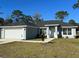 Newly built home with a two-car garage, landscaped yard, and light blue exterior at 14409 Sw 20Th Pl, Ocala, FL 34481