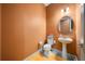 Small bathroom with pedestal sink, toilet, and orange walls at 9406 Dugard Ct, Orlando, FL 32827