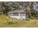 Charming light blue house with screened porch, American flag, and lush landscaping at 13081 E Highway 25, Ocklawaha, FL 32179