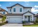 Charming two-story home with a light blue and gray exterior, attached garage, and landscaped yard at 7849 Somersworth Dr, Kissimmee, FL 34747