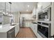 Modern white kitchen featuring stainless steel appliances, quartz countertops, and a stylish island at 7757 Somersworth Dr, Kissimmee, FL 34747