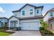 Charming two-story home with a light blue exterior, paved driveway, and attached garage at 7853 Somersworth Dr, Kissimmee, FL 34747