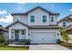 Charming two-story home with a light blue and gray exterior, a paved driveway, and a two-car garage at 7865 Somersworth Dr, Kissimmee, FL 34747