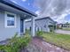 Home entrance with gray exterior, brick walkway, and lush landscaping at 4407 Rapallo Ave, Winter Haven, FL 33884