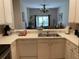 View of the kitchen with white cabinets, a double sink, and a pass-through window to the living area at 409 Lucaya Loop # 409, Davenport, FL 33897