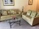 Living room with two green sofas, a glass-top coffee table, and an end table at 409 Lucaya Loop # 409, Davenport, FL 33897