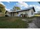 Rear view of a single-story house with a covered patio, metal roof, and spacious yard at 4915 Mount Pleasant Rd, Groveland, FL 34736