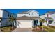 Two-story house with light blue siding, white garage door, and palm trees at 1166 Aloha Blvd, Davenport, FL 33897