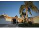 Front view of tan house with palm trees and a landscaped yard at 761 Taos Way, The Villages, FL 32162