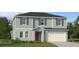 Two-story house with light teal siding, red door, and attached garage at 1299 Inkberry Cir, Deland, FL 32720
