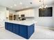 Bright kitchen featuring a blue island, white cabinets, and stainless steel appliances at 319 Ravenshill Way, Deland, FL 32724