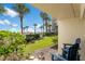 Private patio with ocean view, two chairs, and lush tropical landscaping at 2700 Ocean Shore Blvd # 111, Ormond Beach, FL 32176