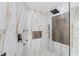 Spa-like shower with marble walls, herringbone tile, and rainfall shower head at 1978 Country Club Dr, Port Orange, FL 32128