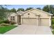 Tan two-story house with two-car garage, lush landscaping, and a manicured lawn at 509 W Victoria Trails Blvd, Deland, FL 32724
