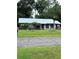 Ranch style home with metal roof, fenced yard, and palm trees at 24008 Ermine Rd, Astor, FL 32102