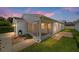White house exterior with screened porch and landscaped yard at dusk at 1106 Carvello Dr, The Villages, FL 32162
