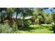 Home's side yard, showing the house partially obscured by trees and vegetation at 711 Sunset Ave, Orange City, FL 32763