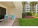 Small patio with teal chairs and side table, overlooking lawn at 4175 S Atlantic Ave # 1130, New Smyrna Beach, FL 32169