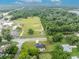 Aerial view of a house nestled in a green landscape, with roads and other buildings visible in the distance at 210 E Baxter St, De Leon Springs, FL 32130