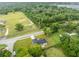 Aerial view of a house on a tree-lined street, surrounded by greenery and open fields at 210 E Baxter St, De Leon Springs, FL 32130